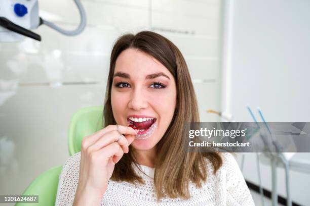 frau hält kieferorthopädische retainer in zahnklinik - zahnspange frau stock-fotos und bilder