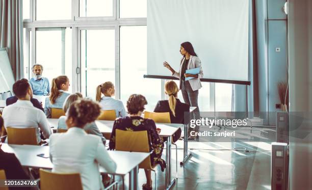 uomini d'affari che ascoltano il presentatore alla conferenza - altoparlante foto e immagini stock