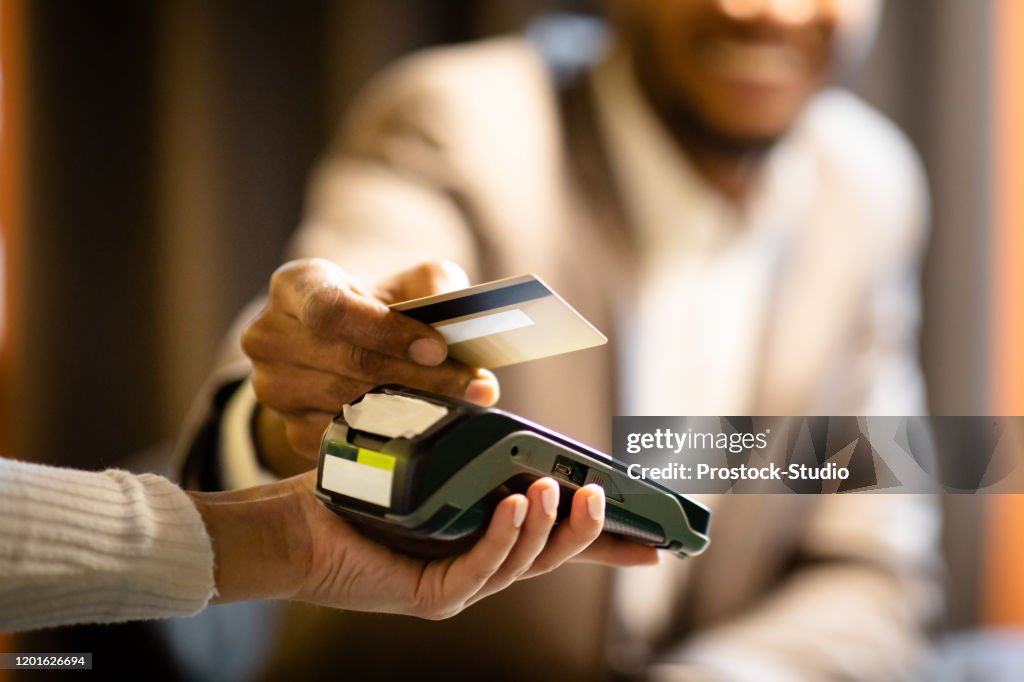 Afro businessman giving credit card to barman