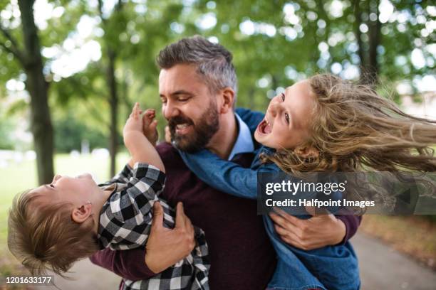 front view of small girls with father standing outdoors in park in city, having fun. - single father stockfoto's en -beelden