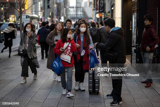 Chinese tourists wearing masks walk through the Ginza shopping district on January 24, 2020 in Tokyo, Japan. While Japan is one of the most popular...