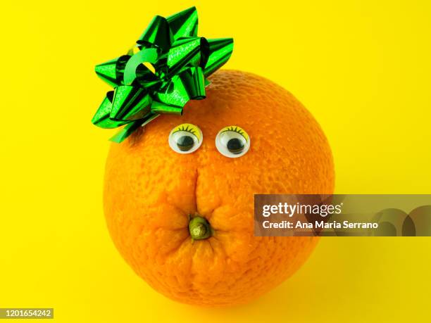 funny food concept. an orange with a flower ornament on a yellow background - ネーブルオレンジ ストックフォトと画像