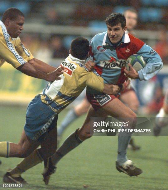 Benjamin Boyet , le joueur Berjallien tente d'éviter le placage de Christophe Larrue et de Gerard Awomo, le 19 mars 1999 au stade Pierre Rajon à...