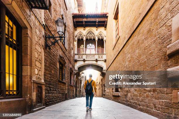 young man with backpack walking on the streets of gothic quarter in barcelona, spain - gotisches viertel barcelona stock-fotos und bilder