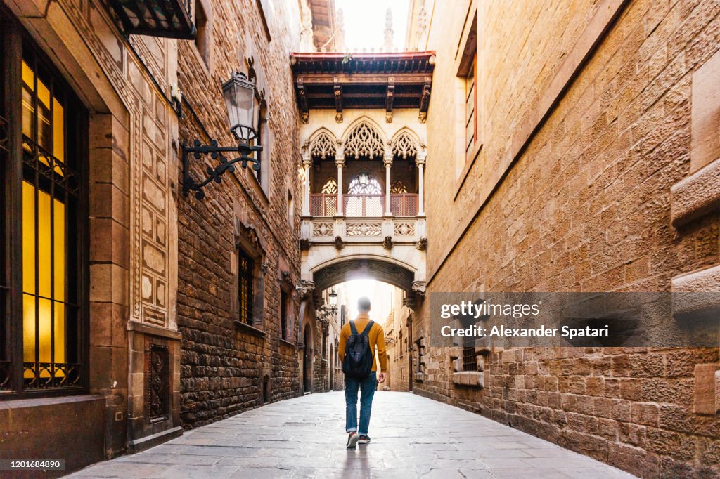 Young man with backpack walking on the streets of Gothic Quarter in Barcelona, Spain