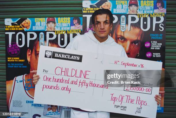 English singer Peter Andre holds an oversized cheque from Top of the Pops magazine payable to the Childline counselling service at a press call in...