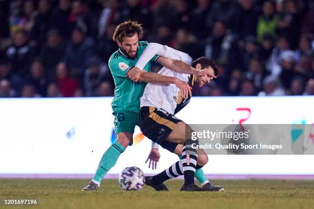 Carlos de la Nava of Unionistas CF competes for the ball with Nacho Fernandez of Real Madrid CF during the Copa del Rey round of 32 match between...