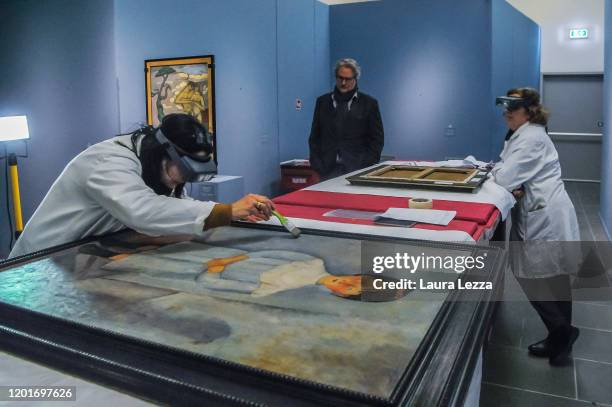 Restorers examine the condition of the painting 'Fillet en blue' by Italian artist Amedeo Modigliani during the dismantling of the exhibition...