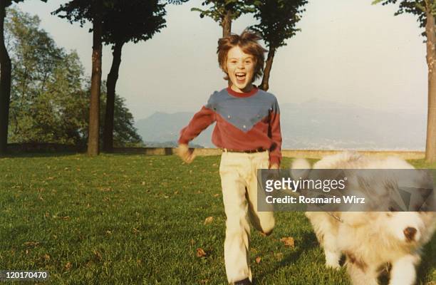 boy running with dog - archival stock-fotos und bilder