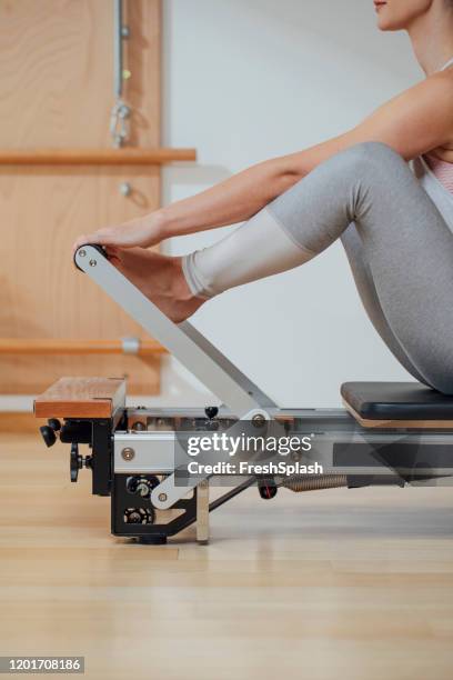 sportswoman doing exercise on pilates reformer - pilates abstract stock pictures, royalty-free photos & images