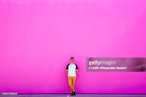 young man standing against pink wall - a la moda stock pictures, royalty-free photos & images