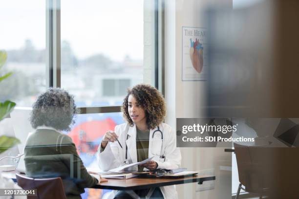 female doctor and unrecognizable mature patient discuss treatment - patient information stock pictures, royalty-free photos & images