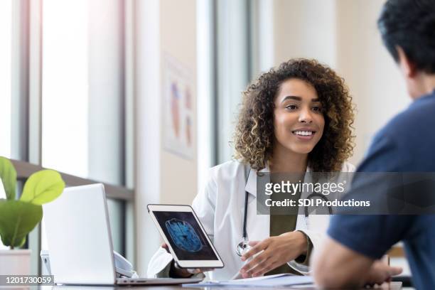 médico sosteniendo tableta que muestra rayos x escucha al paciente - medical x ray fotografías e imágenes de stock
