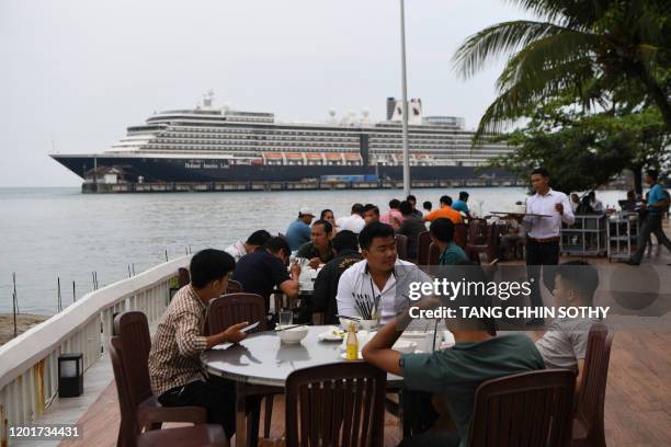 People sit at a restaurant in front of the Westerdam cruise ship in Sihanoukville on February 19, 2020. Cambodia's strongman premier has defended his...