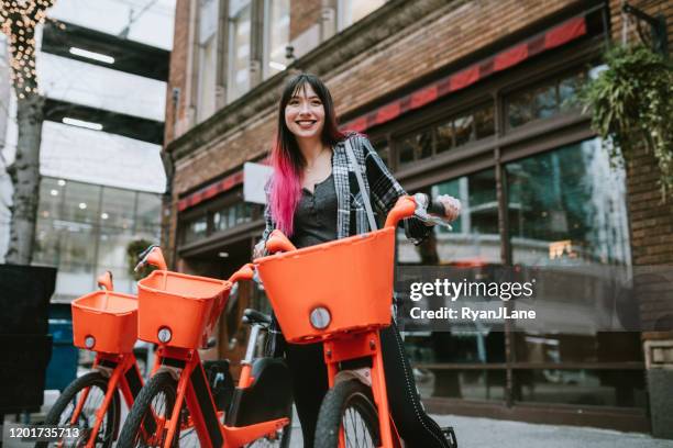 woman in overcast downtown seattle washington with bicycle - bicycle rental stock pictures, royalty-free photos & images