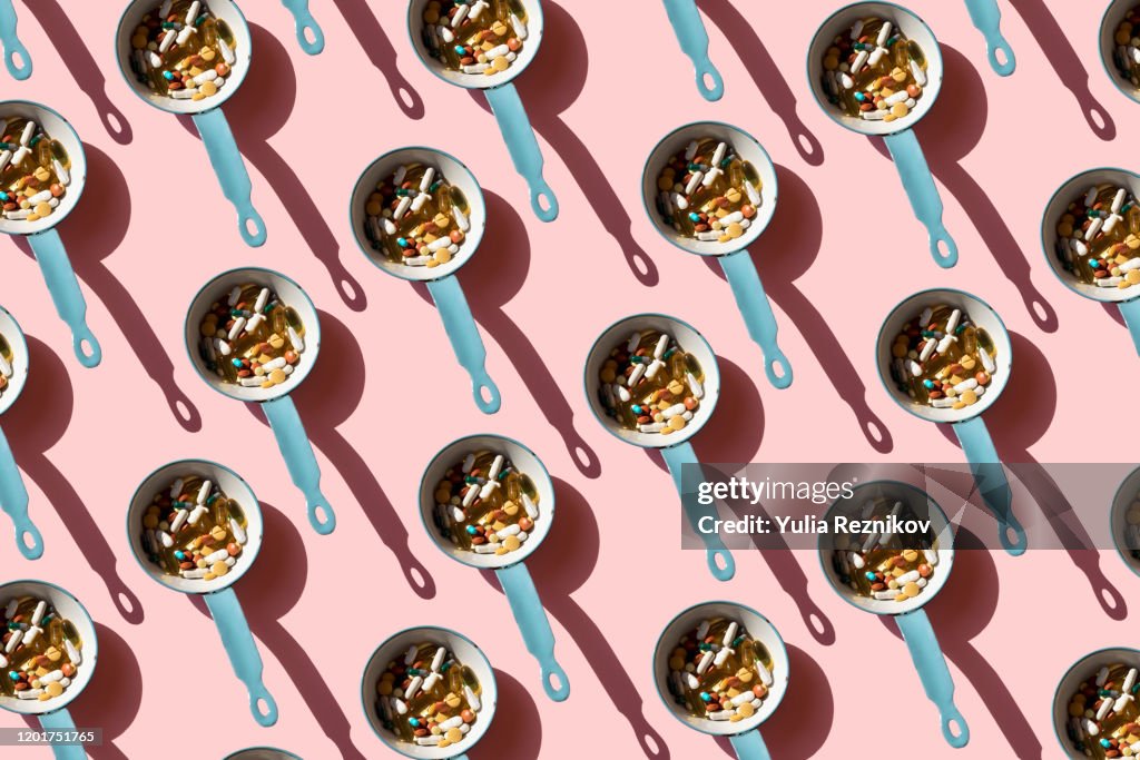 Top view of pan full of various pills and tablets on the blue background