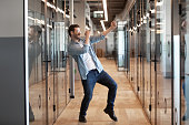 In office hallway dancing worker got promotion celebrating business success
