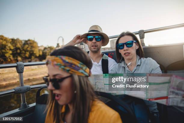 couple looking at a map while riding on a open-air bus - open top bus stock pictures, royalty-free photos & images