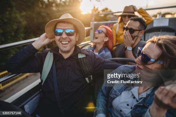 cheerful group of traveling tourists enjoying a tour ride on an open-air bus - party bus stock pictures, royalty-free photos & images