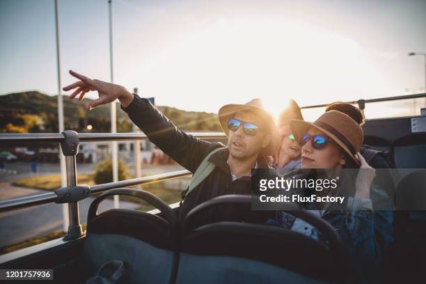 man showing the city to his wife while riding on an open-air bus - open top bus stock pictures, royalty-free photos & images