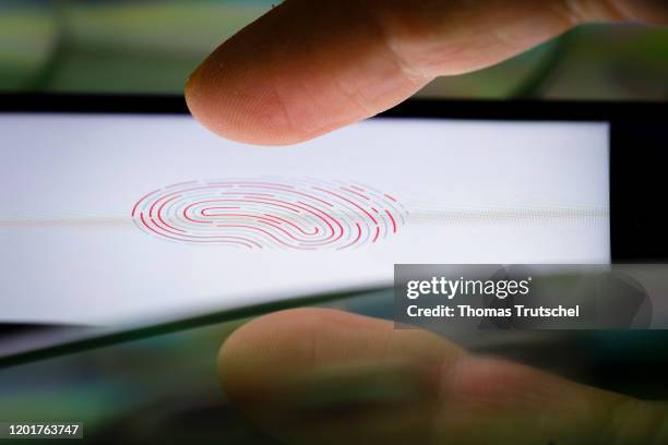 Symbol photo on the subject of Touch ID. A finger is held on the display of an Apple iPhone, on which the symbol of a fingerprint can be seen on...