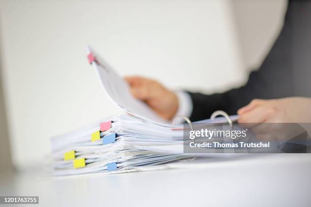 Symbol photo. A man leafs through a file folder with documents, which is lying on a table on February 18, 2020 in Berlin, Germany.