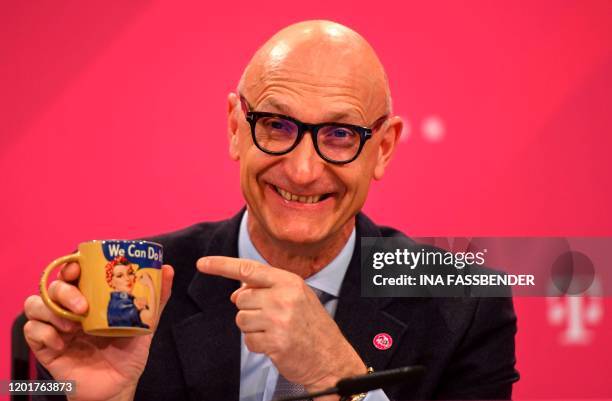 The CEO of German telecommunications giant Deutsche Telekom Timotheus Hoettges points to a coffee mug featuring Naomi Parker Fraley and reading "we...