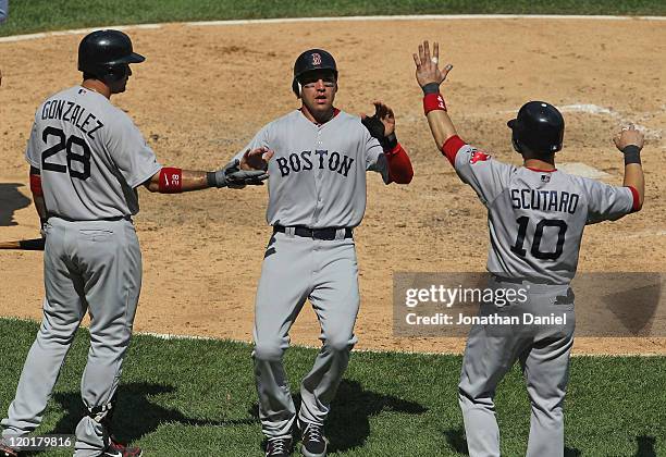 Jacoby Ellsbury of the Boston Red Sox is welcomed by teammates Adrian Gonzalez and Marco Scutaro after scoring in the 7th inning against the Chicago...