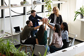 Diverse office staff giving high five celebrating success showing unity