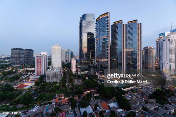 modern luxury office and condominium towers contrasts with run down poor residential district in jakarta - tillväxtmarknad bildbanksfoton och bilder