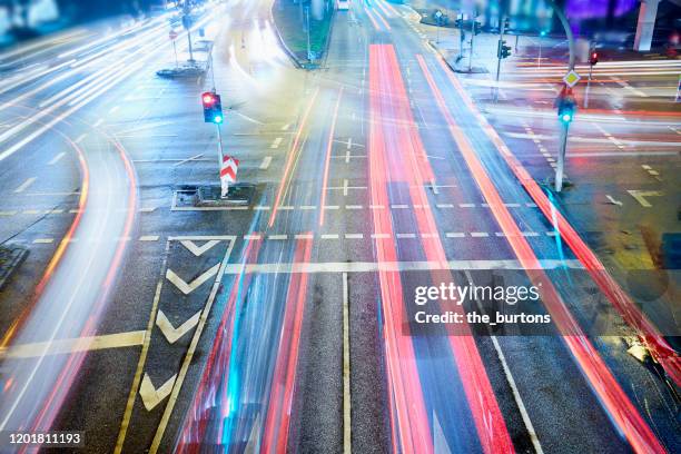 high angle view of crossroad and traffic lights with light trails of cars at night - autoverkehr stock-fotos und bilder