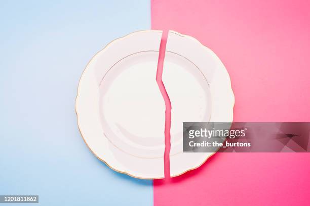 broken plate on blue and pink background - halved stock-fotos und bilder