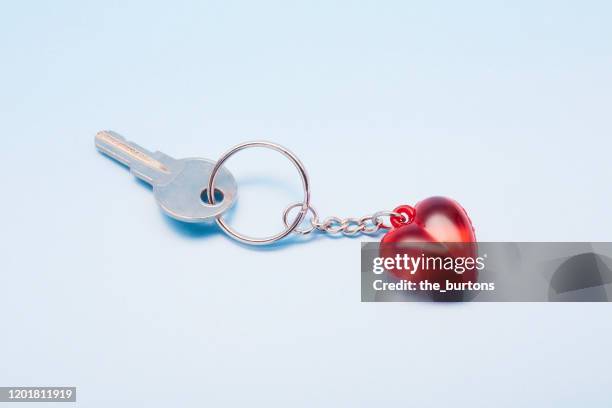 key on a keyring in heart shape on blue background - trousseau de clés photos et images de collection