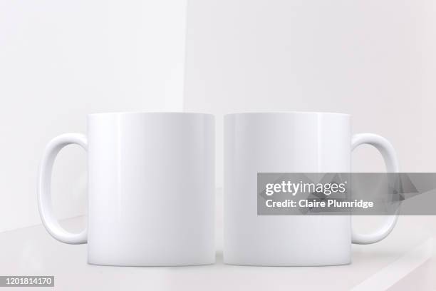 white mug mockup. two white coffee mugs on a shelf with a white background. perfect for businesses selling mugs, just overlay your quote or design on to the image. - twee objecten stockfoto's en -beelden