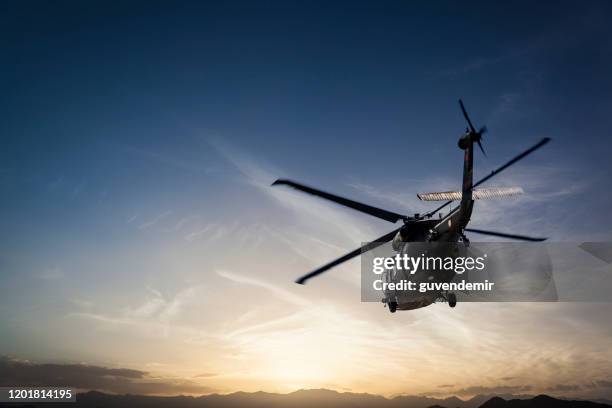 fotos militärhubschrauber fliegen gegen sonnenuntergang - rettungshubschrauber stock-fotos und bilder
