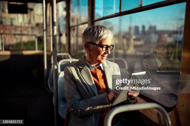 lächelnde geschäftsfrau auf dem weg zur arbeit - laptop on bus stock-fotos und bilder