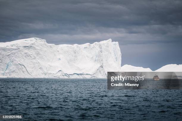 exploration boat in front of huge greenland icebergs ilulissat arctic waters - nuuk greenland stock pictures, royalty-free photos & images