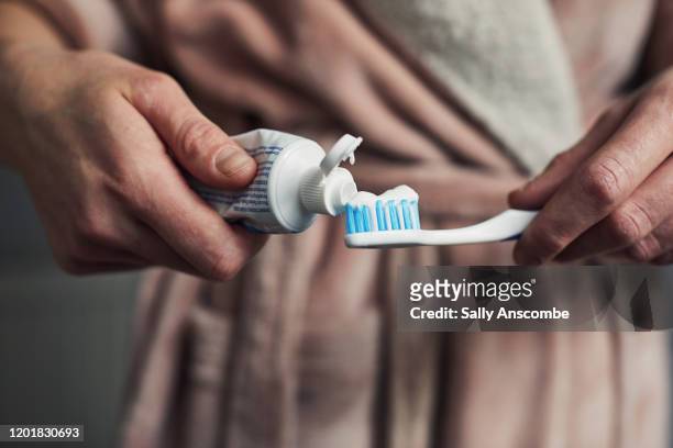 woman putting toothpaste on a toothbrush - lavarse los dientes fotografías e imágenes de stock