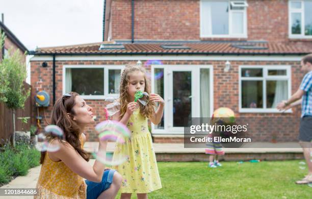 mother and daughter blowing bubbles - uk domestic garden stock pictures, royalty-free photos & images