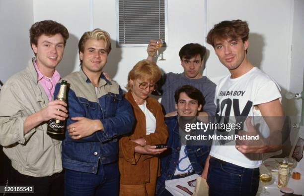 English pop group Spandau Ballet celebrating backstage, circa 1980. Left to right: guitarist Gary Kemp, saxophonist Steve Norman, unknown, drummer...