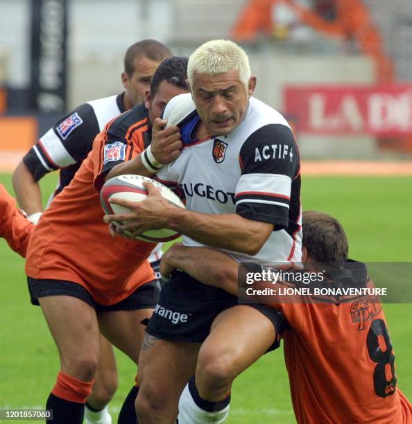 Le joueur du stade toulousain Christian Labit est plaqué sous l'oeil de son coéquipier Frédéric Michalac par le joueur du racing club narbonnais...