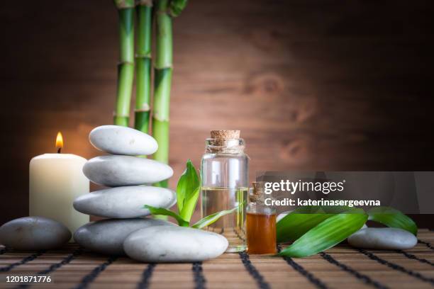 weiße zen-balance steine, eine orchidee blume, eine bambuspflanze und eine kerze auf einem holztisch - ayurveda stock-fotos und bilder