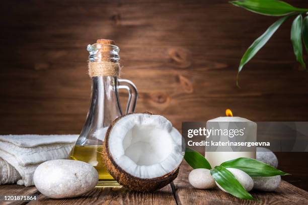 spa still life with coconut, massage oil and candle on a wooden background - coconut oil stock pictures, royalty-free photos & images