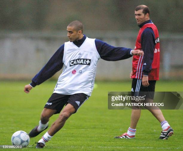 Le meneur de jeu français Zinedine Zidane regarde l'attaquant David Trezeguet tirer au but, le 22 mars 2001 au centre technique de Clairefontaine,...