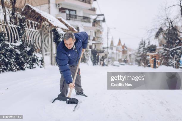 man with snow shovel, winter weather - shoveling driveway stock pictures, royalty-free photos & images
