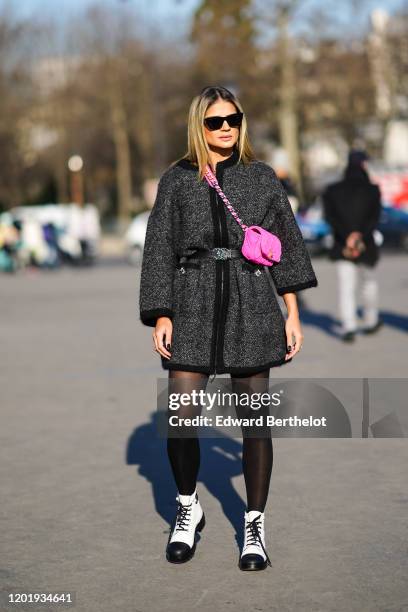 Thassia Naves wears sunglasses, a neon pink Chanel bag, a black and gray jacket, a belt, black tights, black and white shoes with black shoelace,...