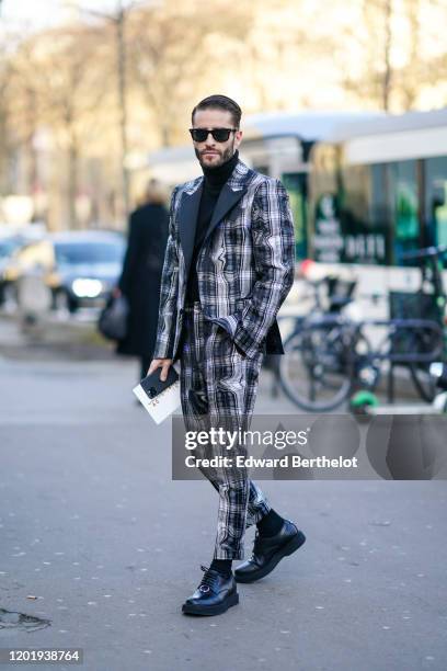 Pelayo Diaz wears sunglasses, a black turtleneck pullover, a checked blazer jacket, suit pants, black leather shoes, outside Schiaparelli, during...