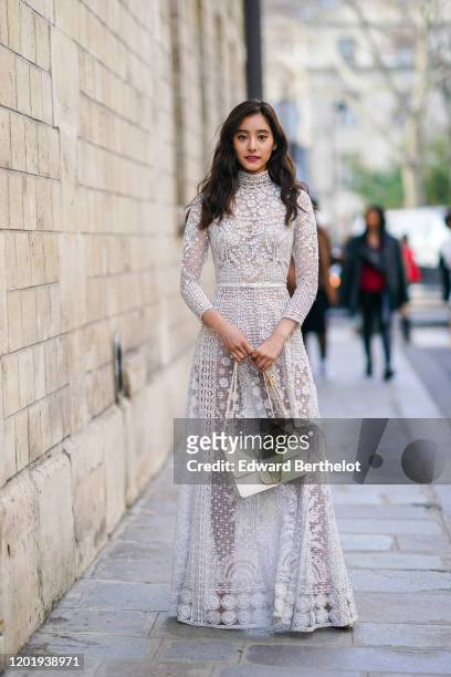 Yuko Araki wears a white lace mesh dress with floral embroidery, a "CD" Dior bag, outside Dior, during Paris Fashion Week - Haute Couture...