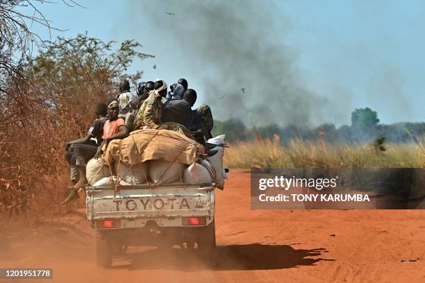 Pick-up truck transporting people and goods drives past burning fields as it heads to Wau on January 31, 2020. - 13,000 civilians shelter under UN...
