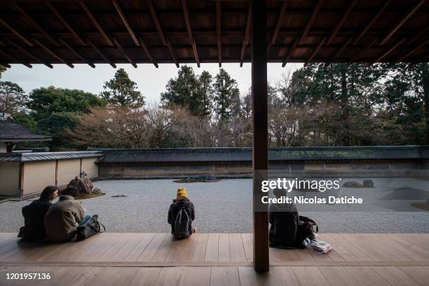 Few tourists sit to enjoy the rock garden in one of the famous landmark an empty Ryoan-ji temple in Japanese old capital city Kyoto. Following the...